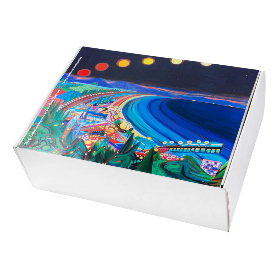 Moonlit Santa Cruz Cookie Gift Box – white gift box featuring Bay Moon by local artist Tessa Hope Hasty. The painting showcases a vibrant, colorful night scene of the Santa Cruz Beach Boardwalk under a moonlit sky, with ocean waves and glowing amusement park lights.