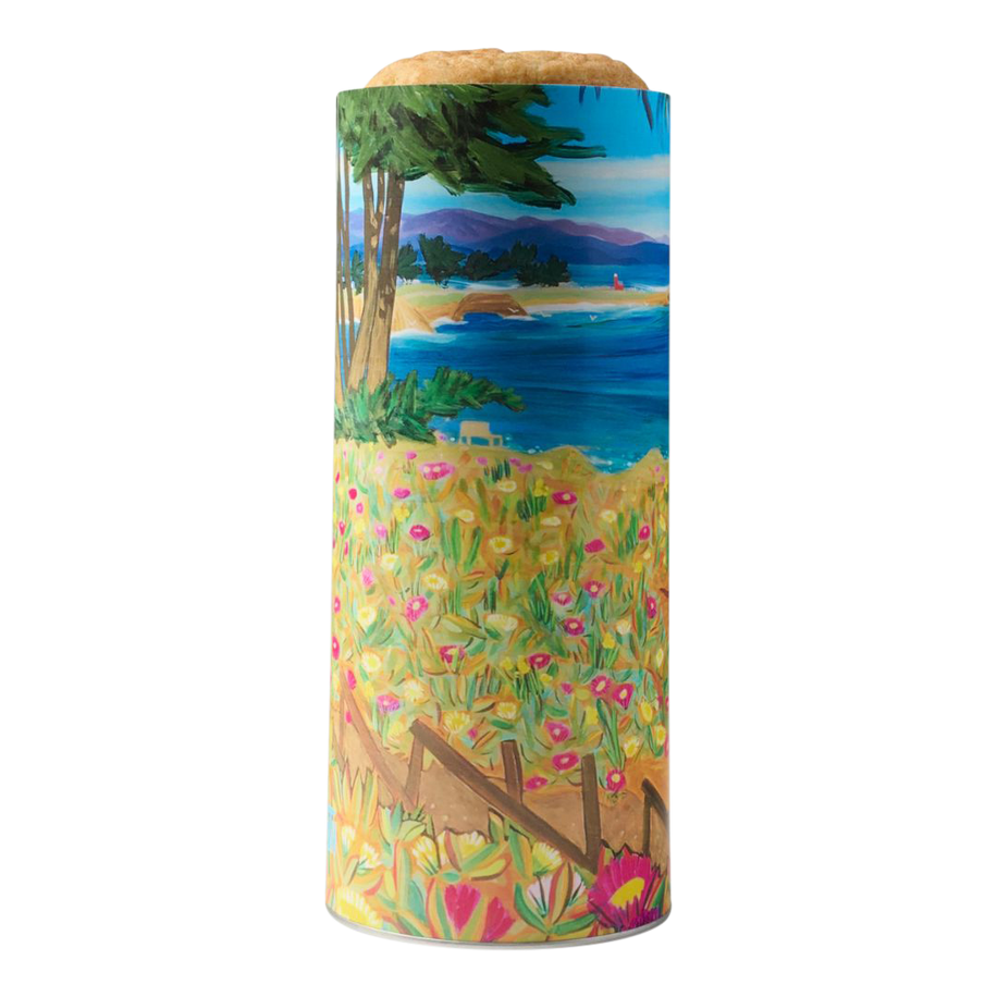 West Cliff Cookie Gift Tower, with painting Out Front by local artist Tessa Hope Hasty, featuring a scenic coastal view of sand, surf, wildflowers, and cypress trees along the Monterey Bay shoreline.